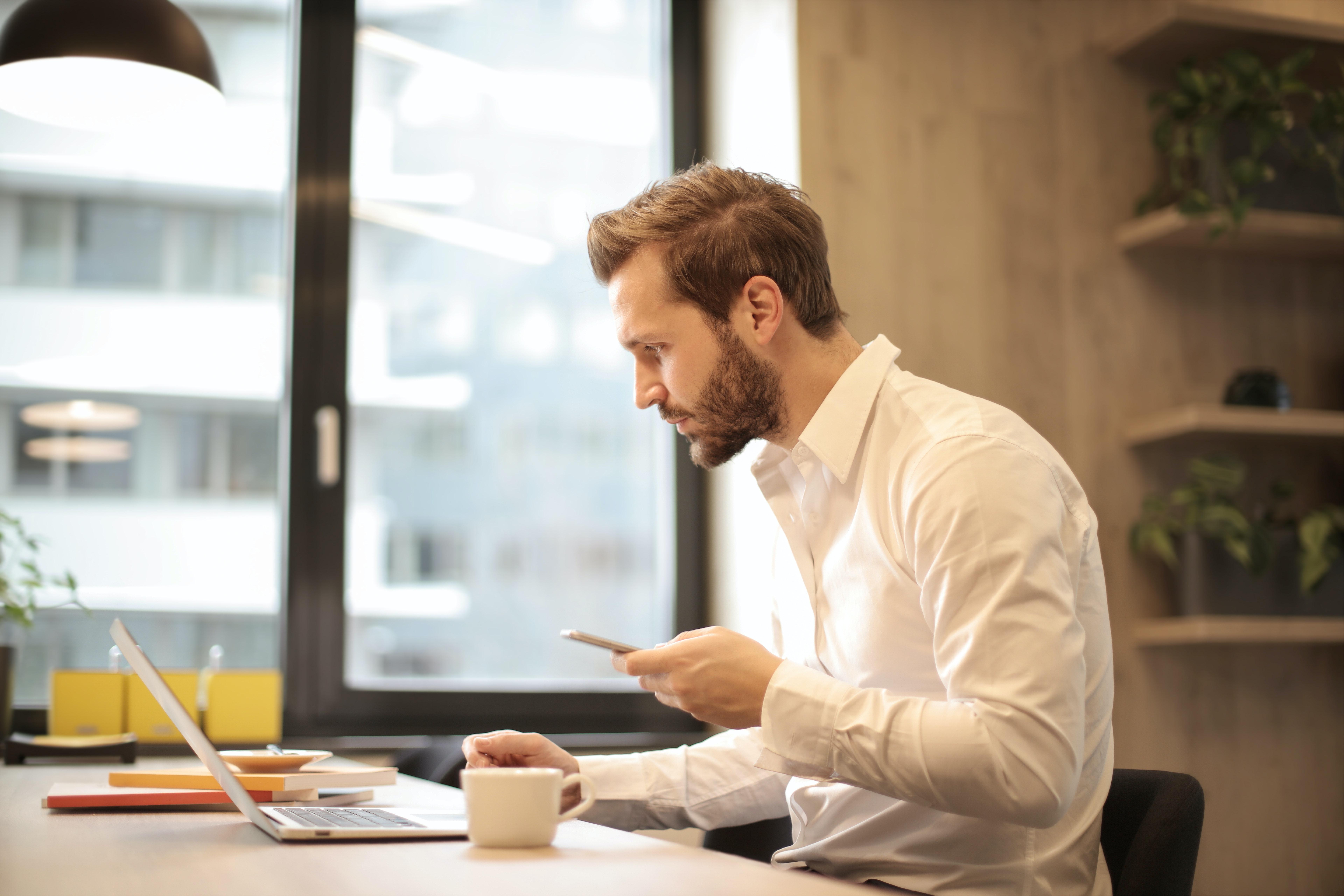 Man reading phone and eating breakfast at same time.