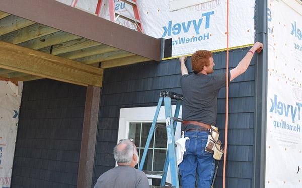 student siding a house